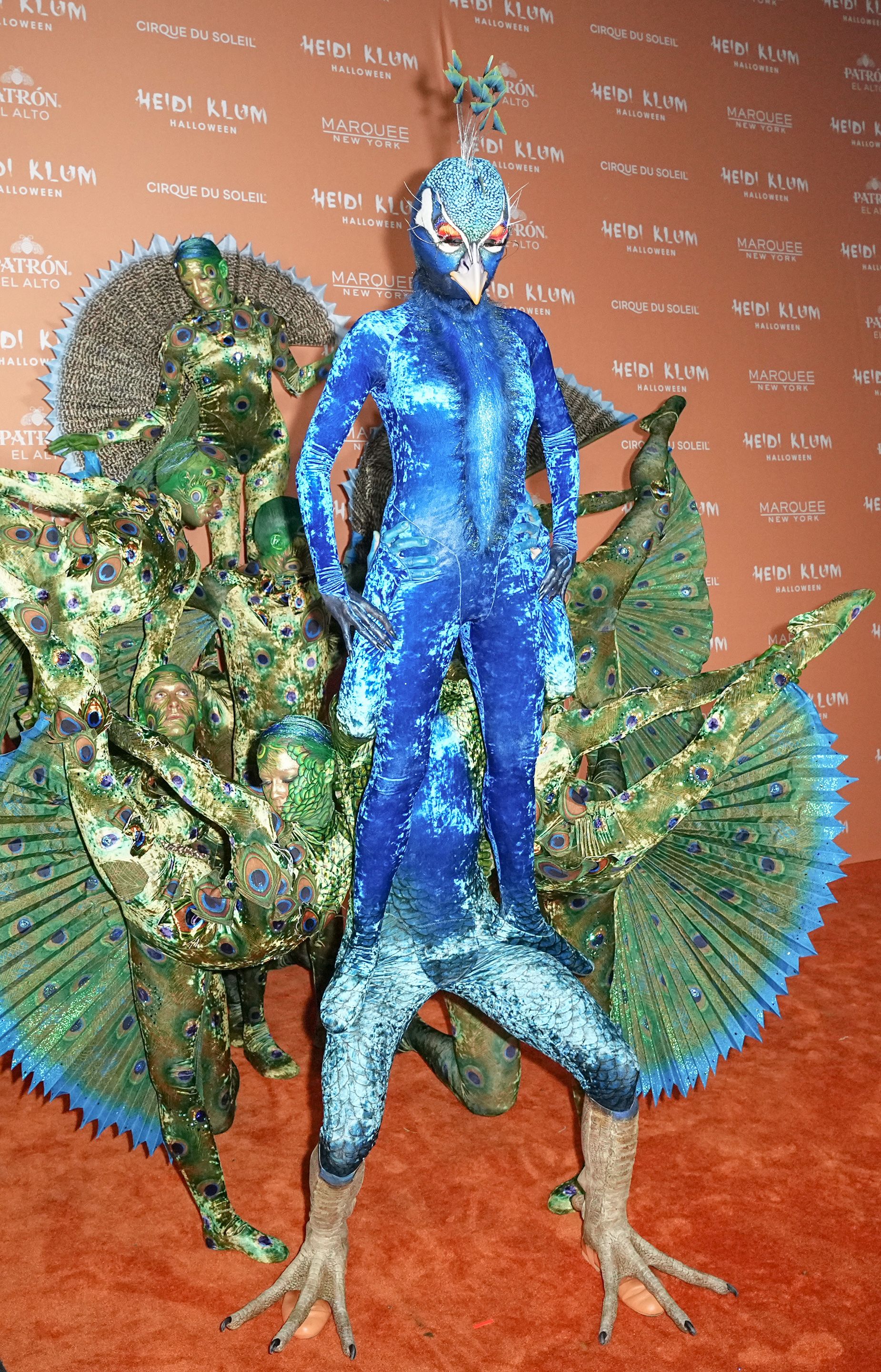 Queen of Halloween, Heidi Klum, came dressed as a peacock — her costume was completed by a team of acrobats dressed as her plume of feathers.
